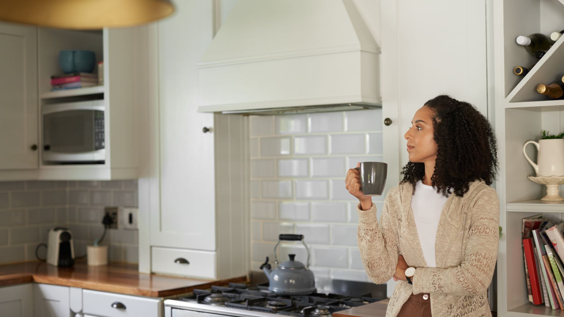 Woman standing in a kitchen holding a mug, representing everyday situations discussed under the Romeo and Juliet law